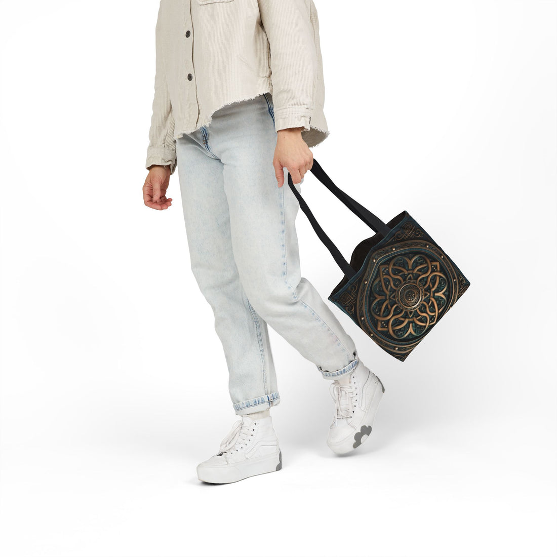 Person carrying Celtic Shield Knot Turquoise and Bronze Tote Bag with black handles and intricate design.
