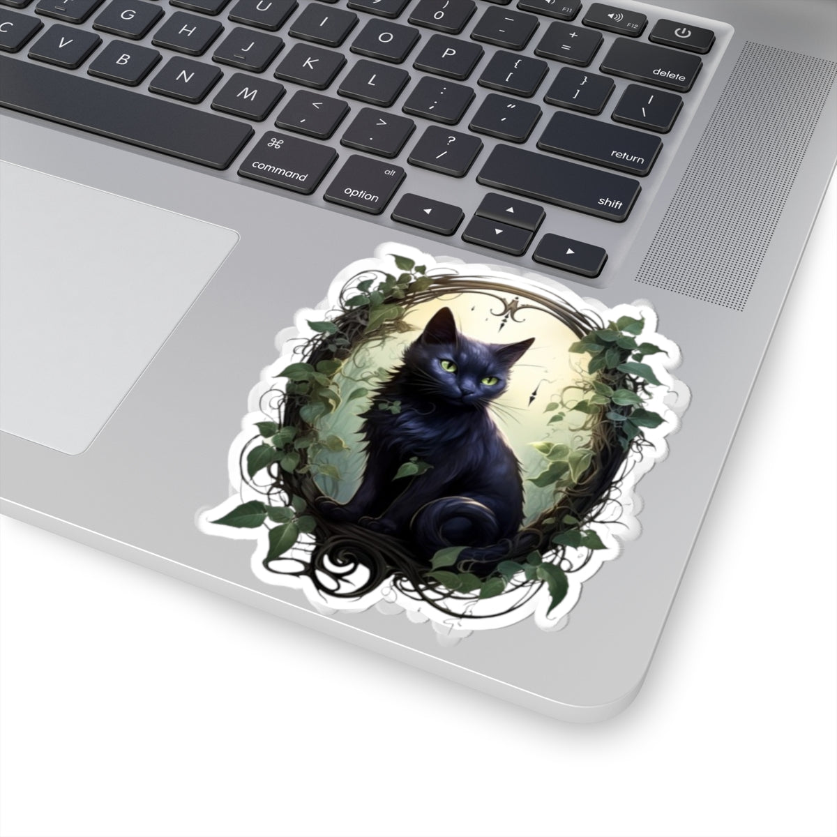Laptop with a decorative sticker of a black cat surrounded by leaves on the palm rest area.