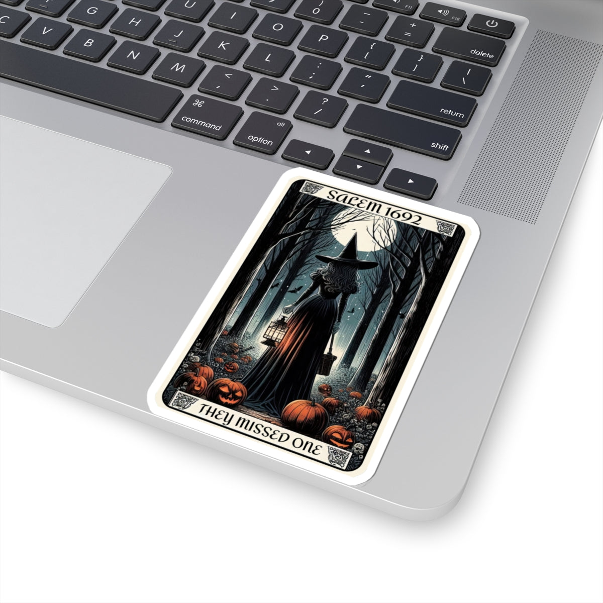 Halloween-themed card with a witch and pumpkins on a laptop keyboard