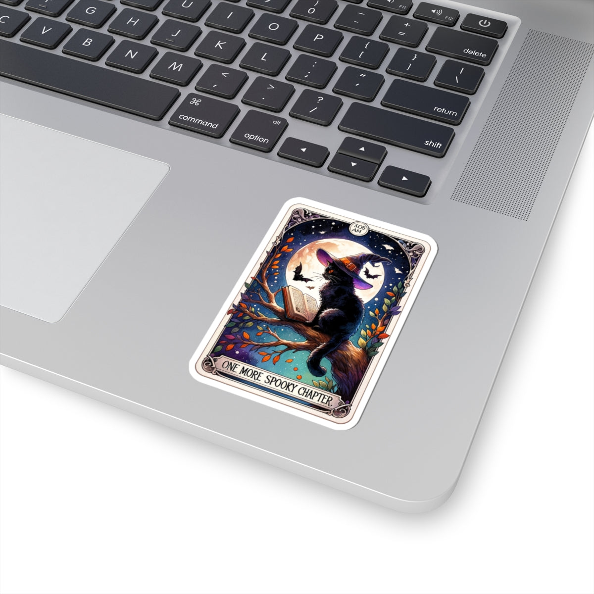 Laptop with a sticker of a cat in a tree and moon on a branch