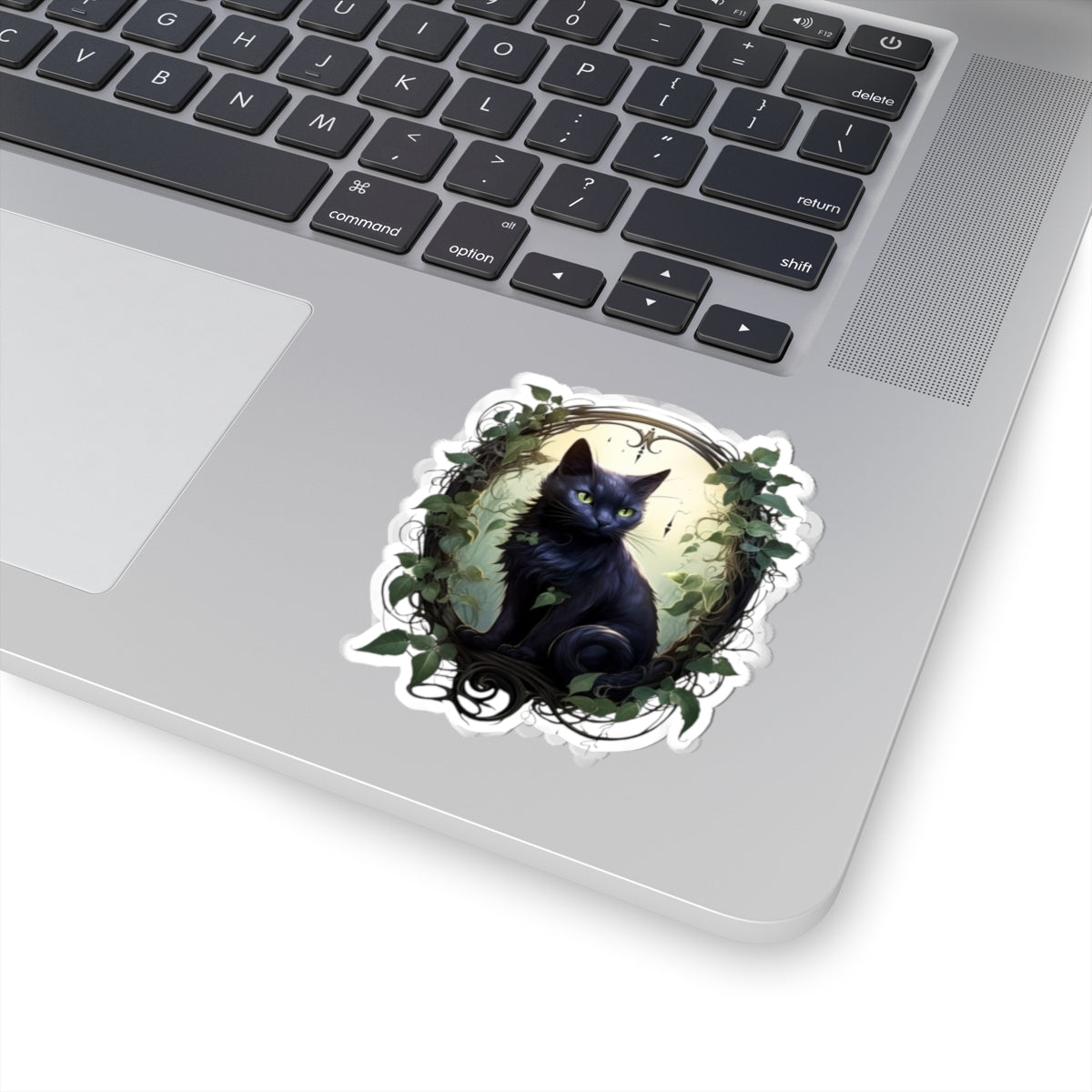 Laptop with a decorative sticker of a black cat on a white surface